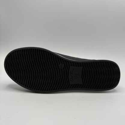 The black textured rubber outsole of a shoe, showing the embossed logo  on a light gray studio background.