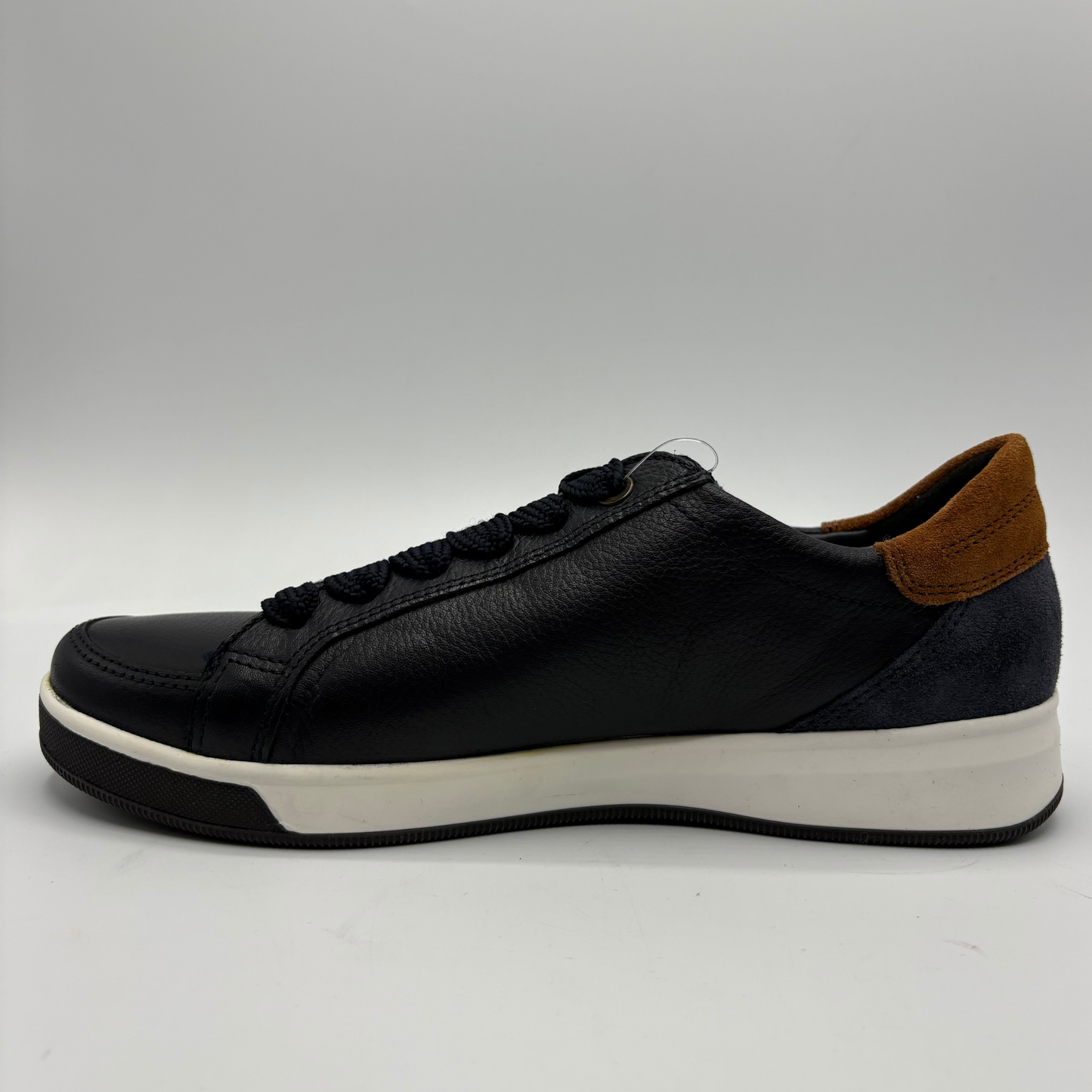 A leather low-top sneaker with a thick white platform sole, black laces, and a brown suede heel accent, shown in a side profile on a light gray background.