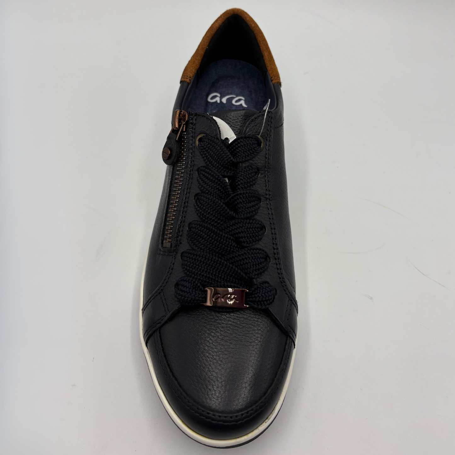 A leather low-top sneaker with a side zipper, black braided laces, a metallic bronze decorative buckle on the laces, and a white rubber sole, shown from a top-down view on a white background.