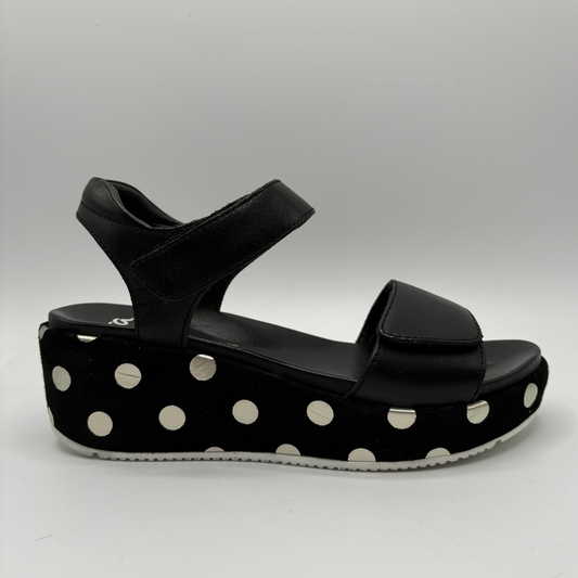 Black sandal with white polka dots on a gray background