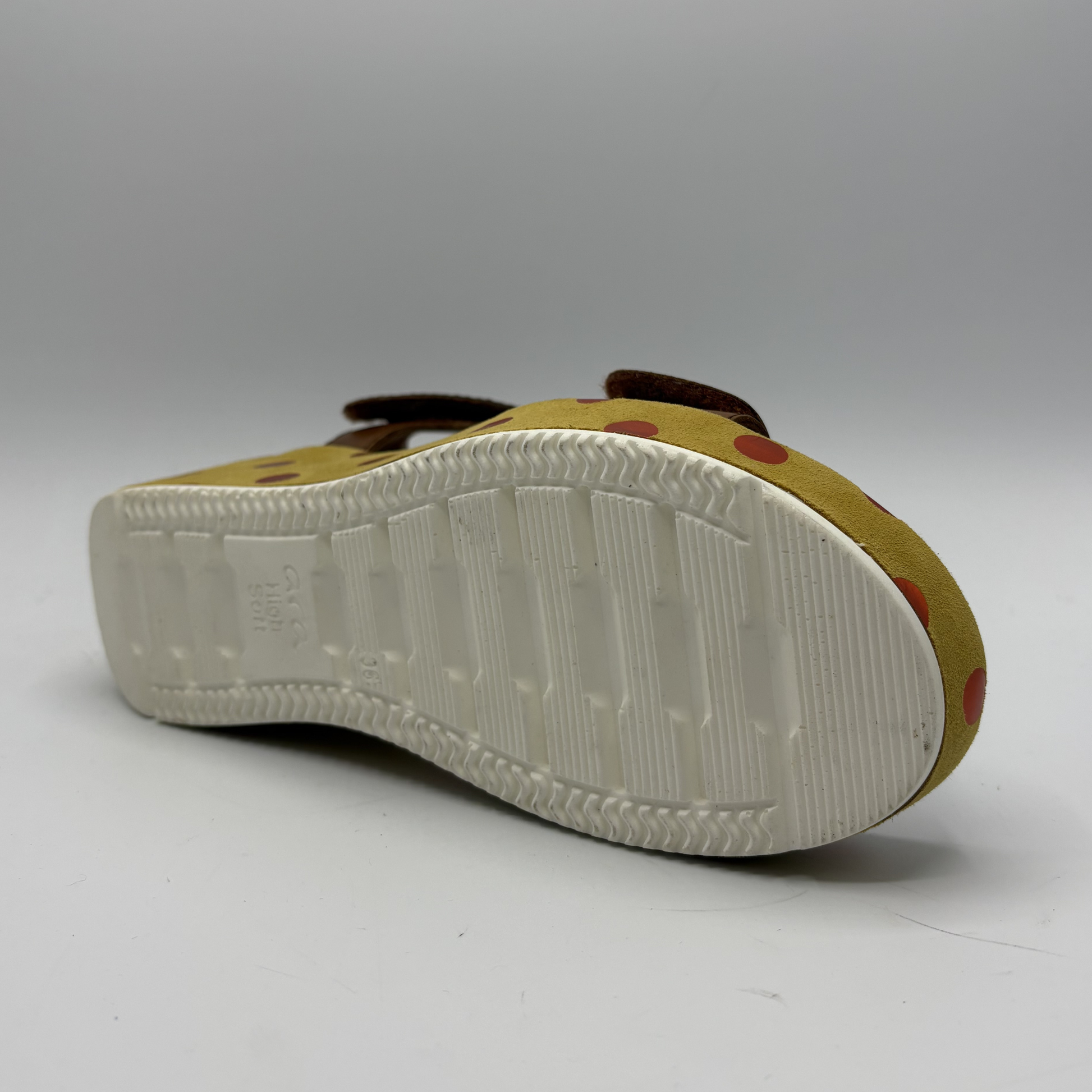 Back view of a sandal with a white sole on a gray background