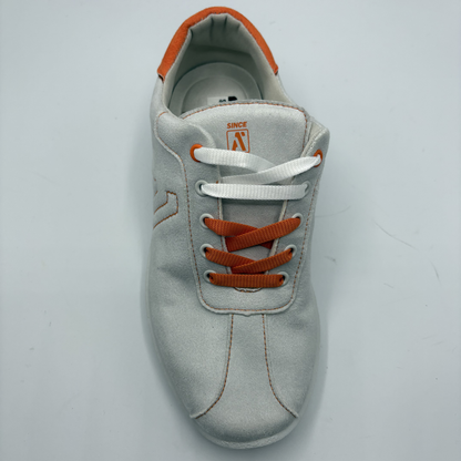 Gray sneaker with orange laces on a light gray background
