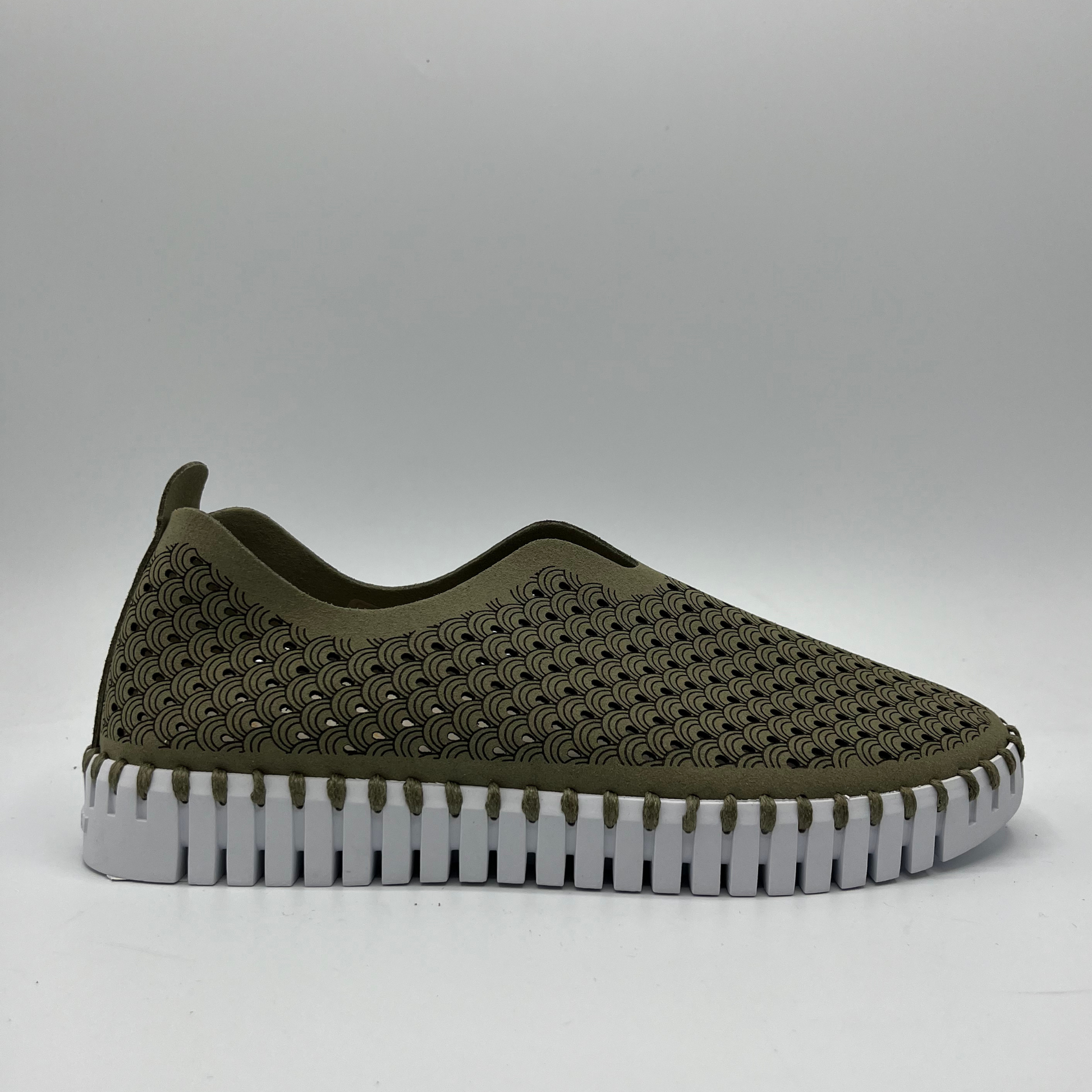 Right facing view of army green slip on shoe with an intricate laser cut upper and white rubber outsole.