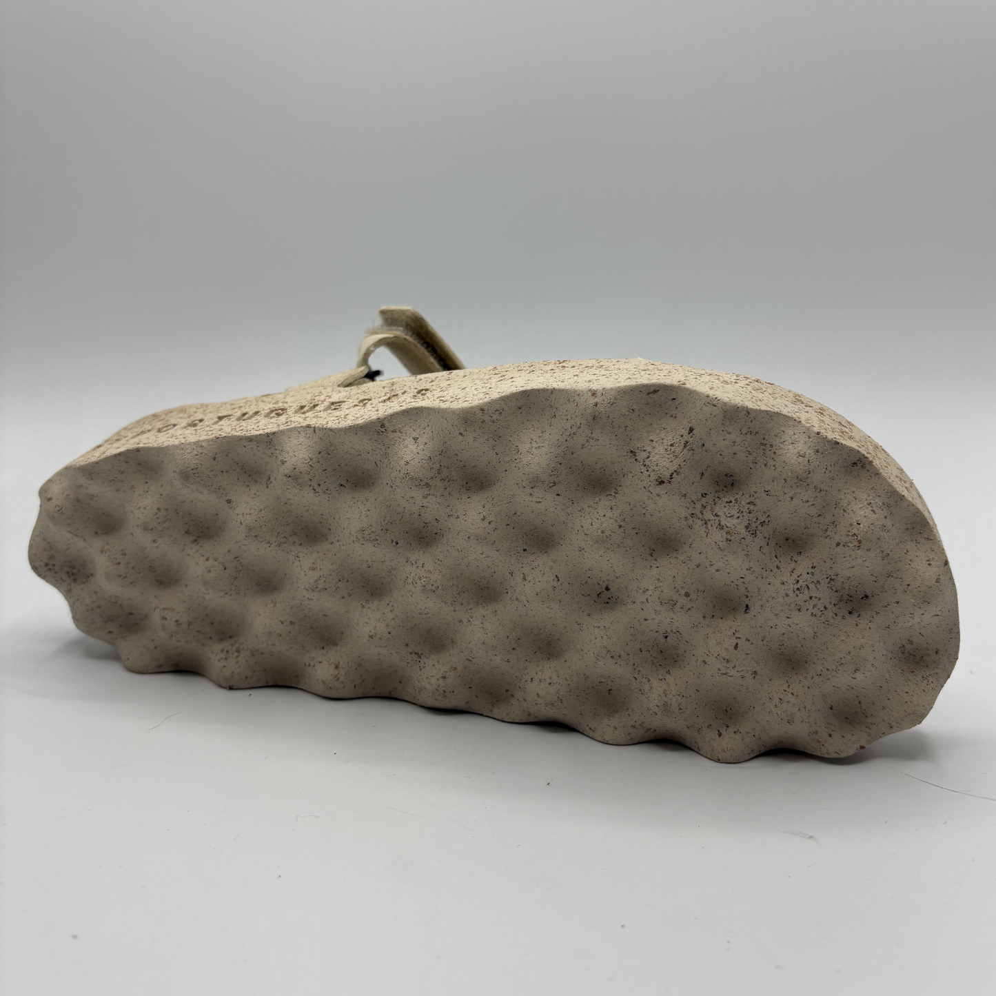 Back view of a sandal sole with textured pattern on a gray background