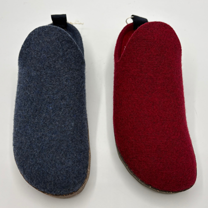 Two slip-on wool shoes side by side on a plain white background, one in dark blue-gray and one in deep red, each with a small black pull tab at the top.