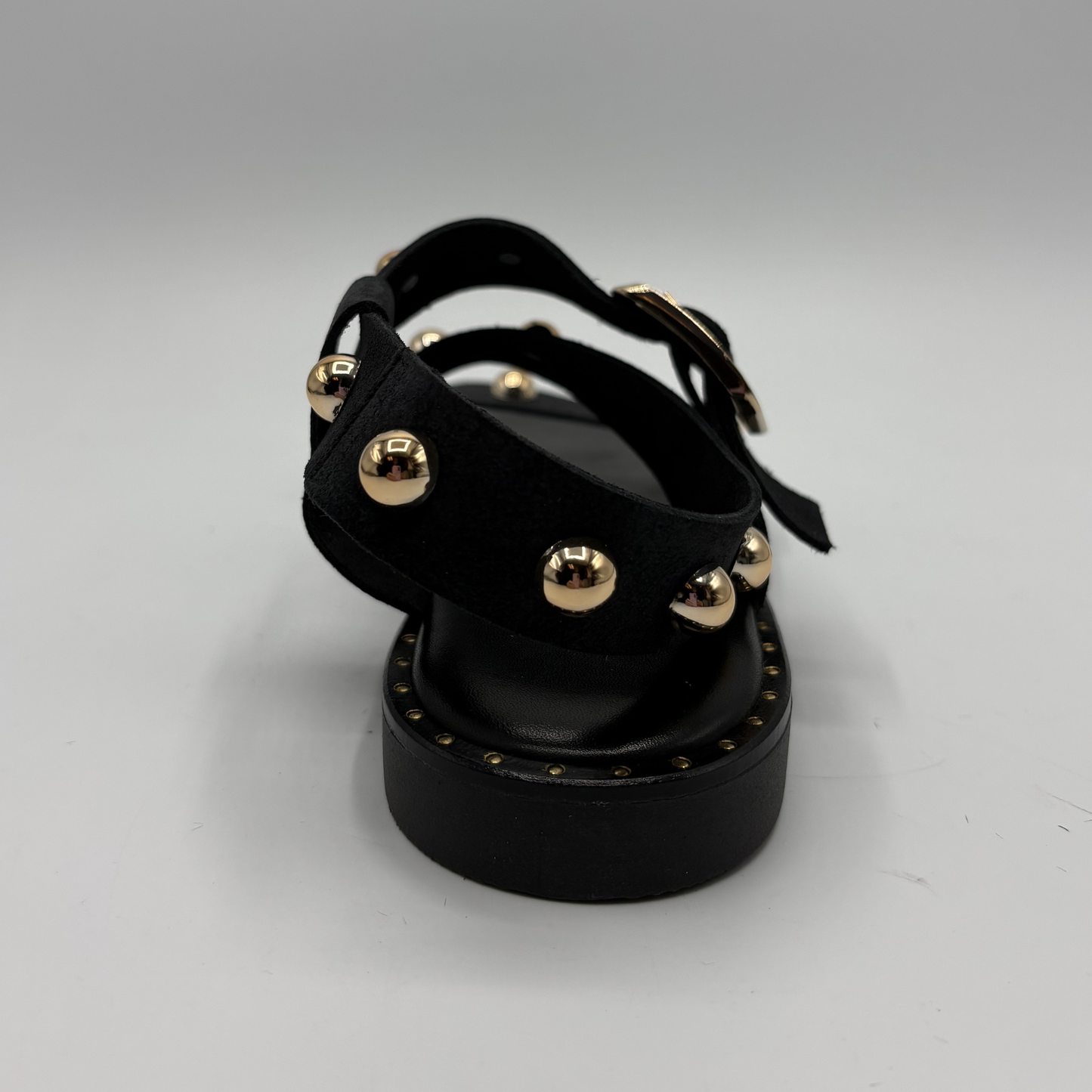 Black sandal with gold studs on a white background
