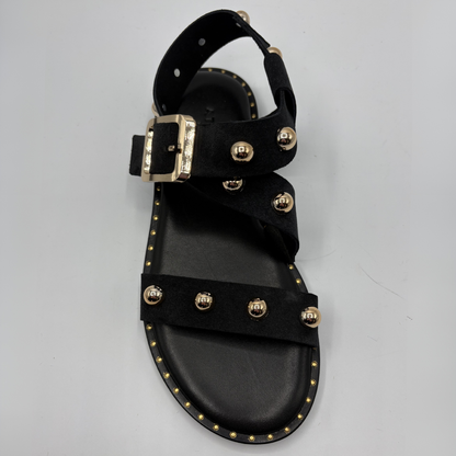 Black sandal with gold buckles and studs on a gray background