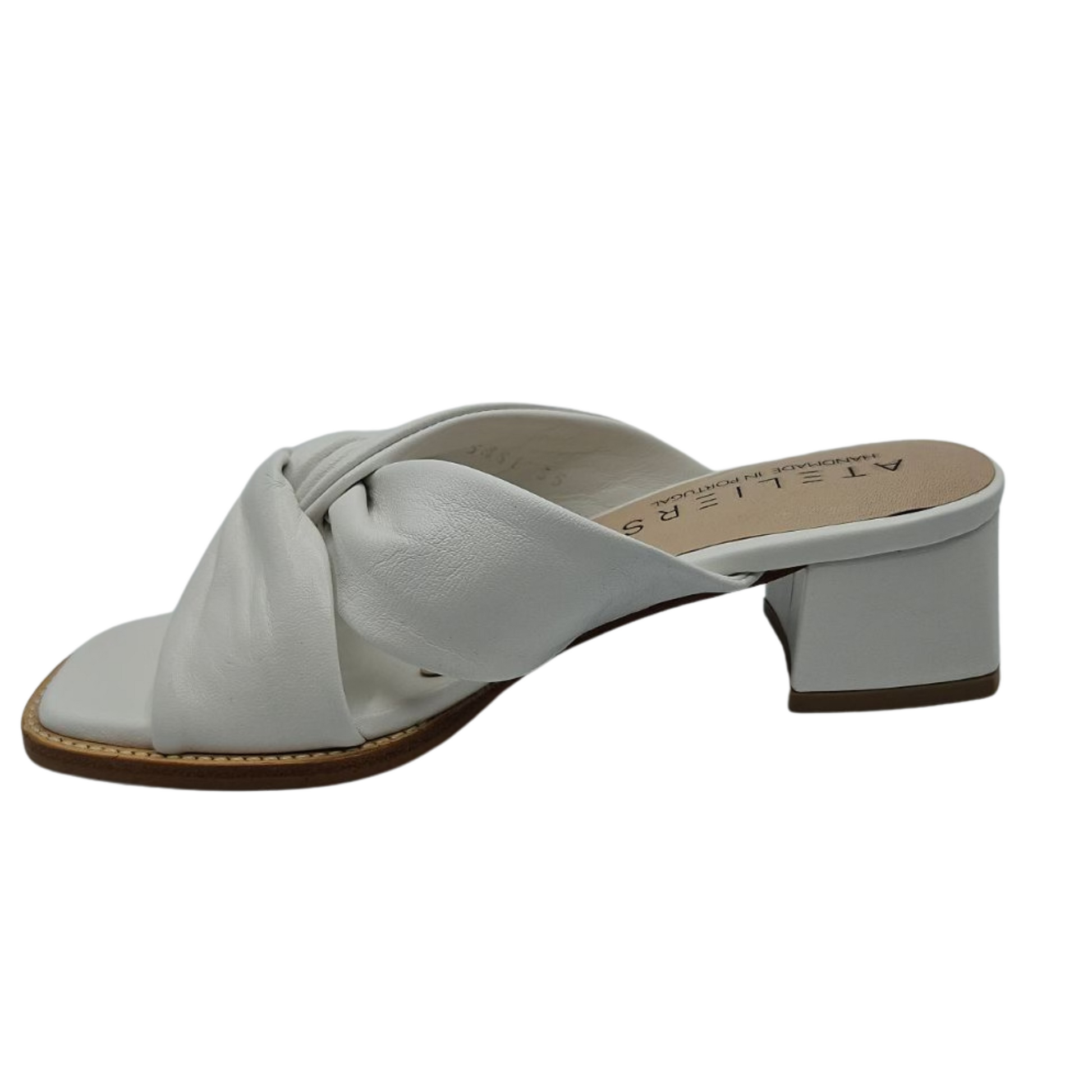 Left facing view of white leather sandals with a soft square toe. These heels have a leather lining and leather wrapped block heel. Knotted straps on upper