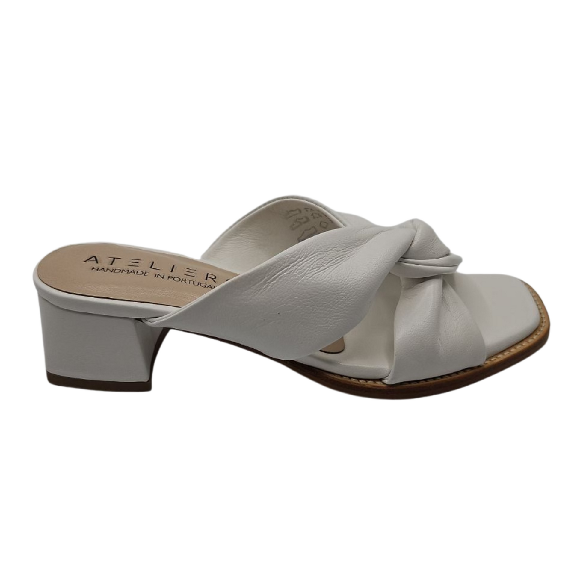 Right facing view of white leather sandals with a soft square toe. These heels have a leather lining and leather wrapped block heel. Knotted straps on upper