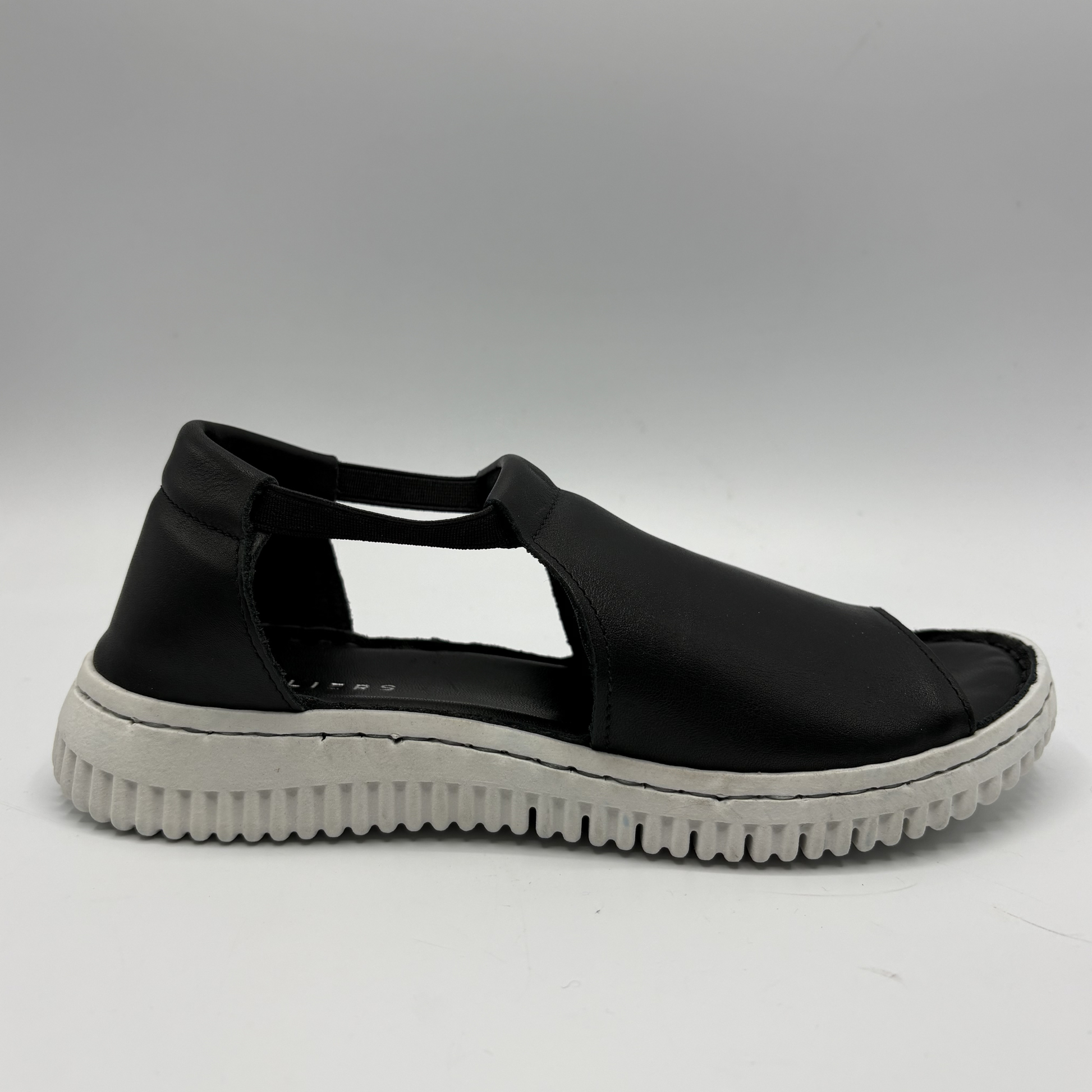 Black sandal with a white sole on a gray background
