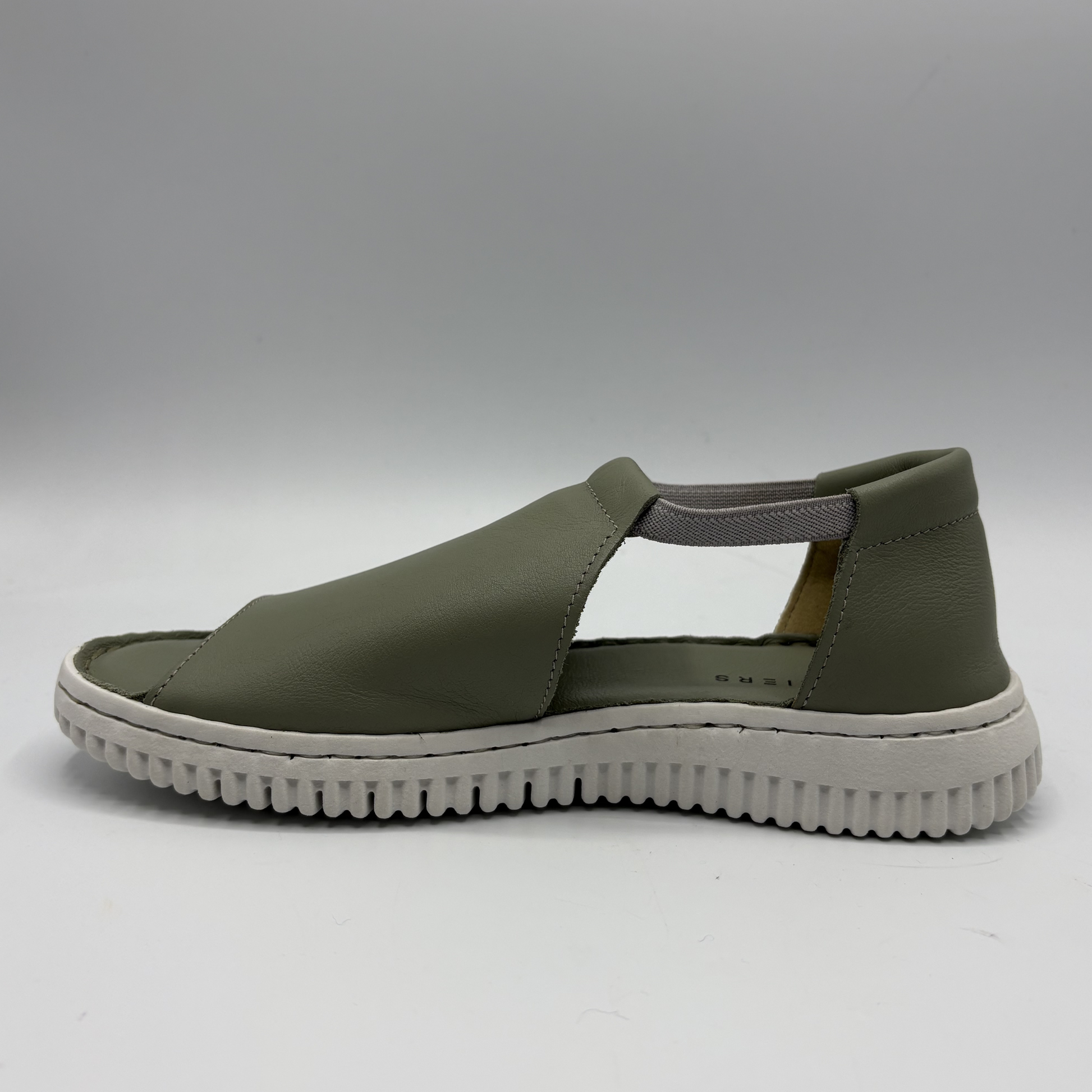 Green sandal with a white sole on a gray background