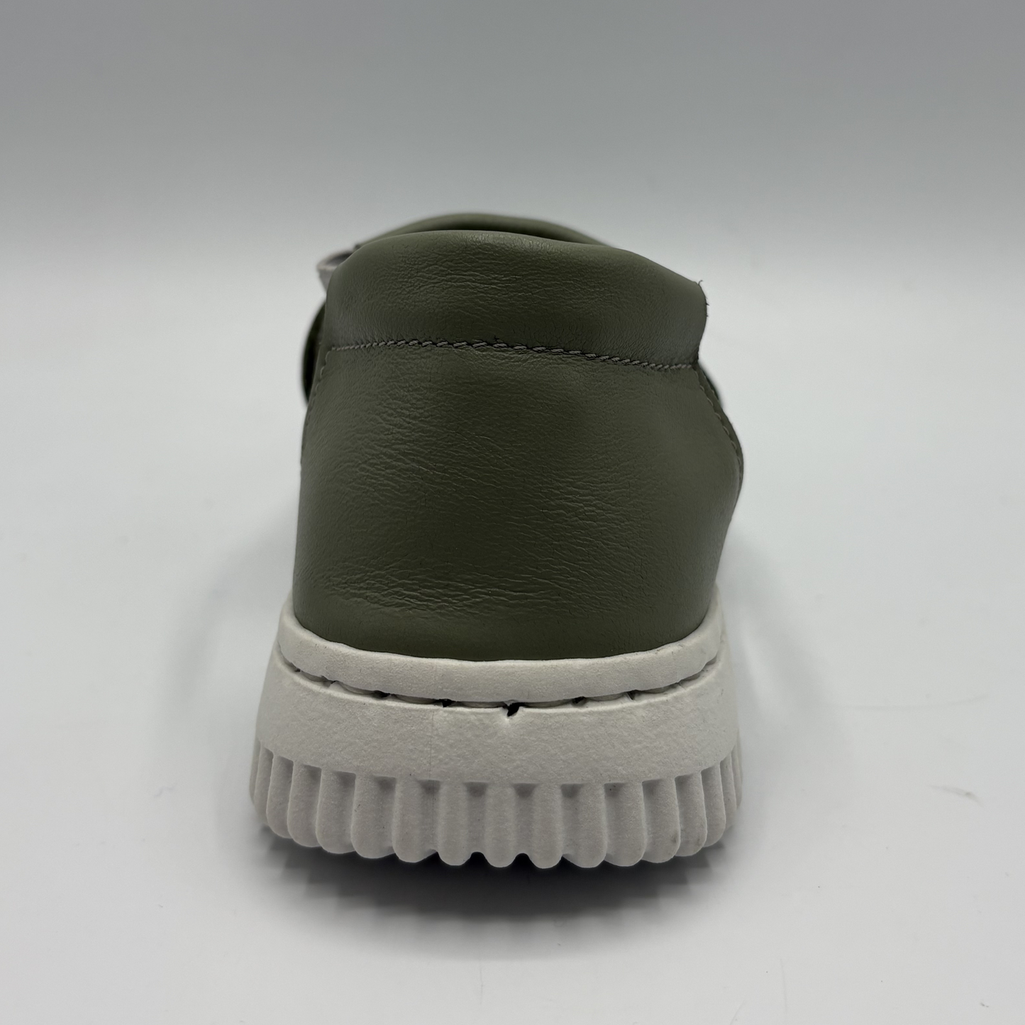 Green slip-on shoe with white sole on a light gray background