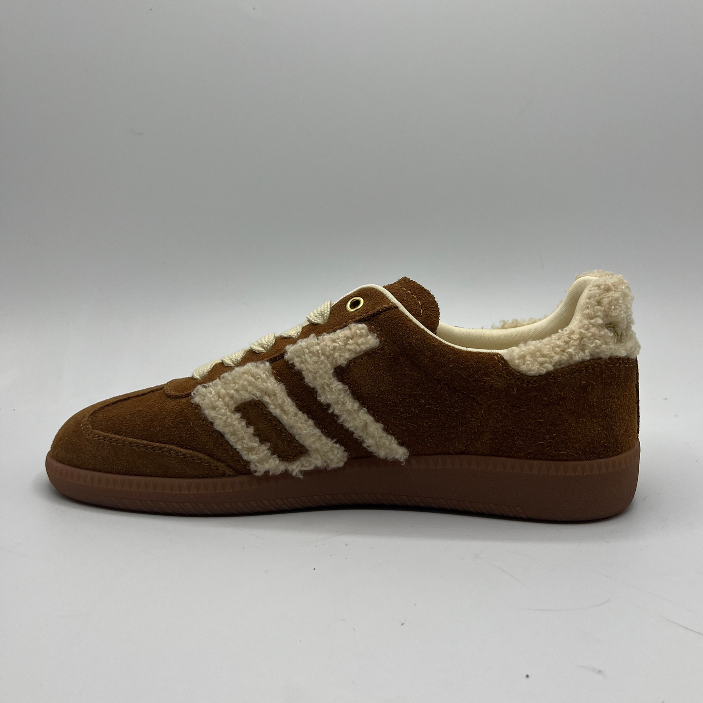 Brown sneaker with white shearling lining on a gray background