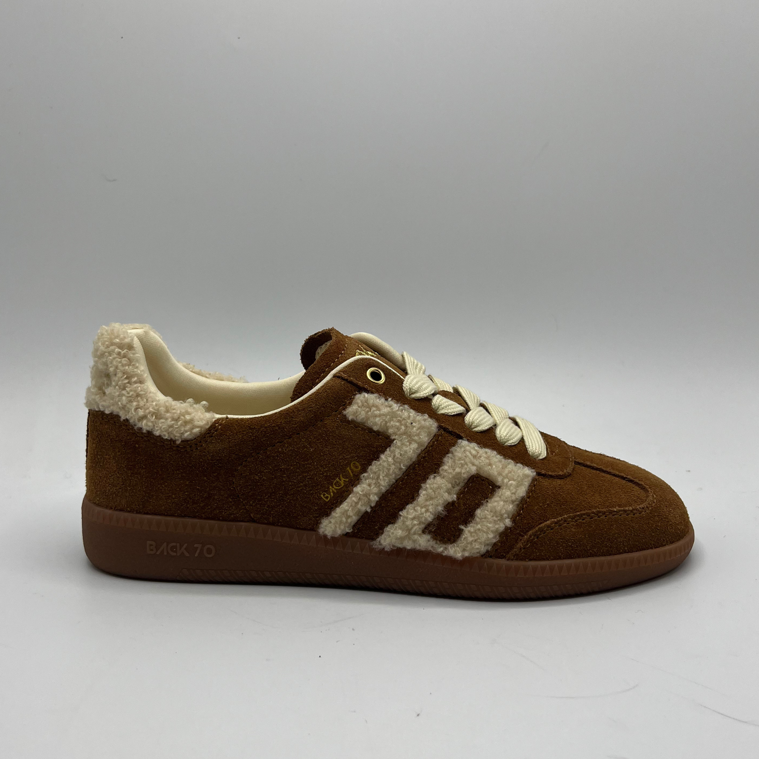 Brown sneaker with white shearling lining on a gray background