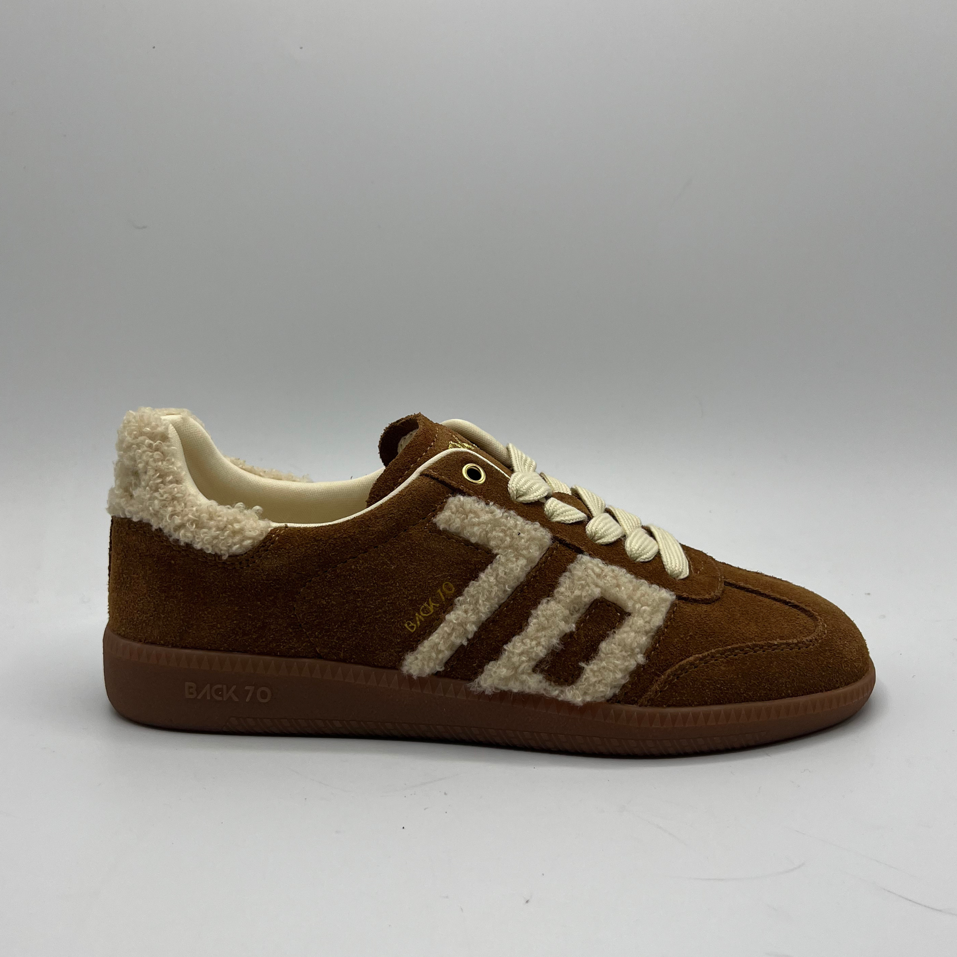 Brown sneaker with white shearling lining on a gray background