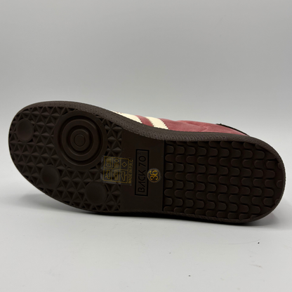 The outsole of a suede sneaker in burgundy and cream, showing the 'BACK 70' markings on the dark brown rubber tread.