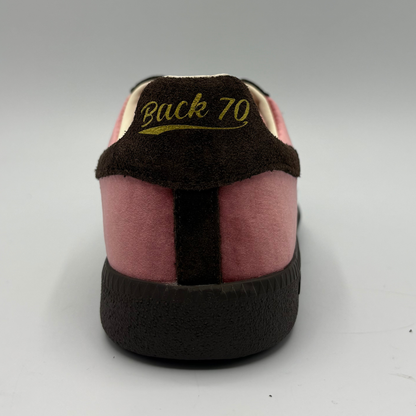 A close-up rear view of a sneaker with pink suede panels, a dark brown heel tab, and yellow text reading 'Back 70' on the heel counter.