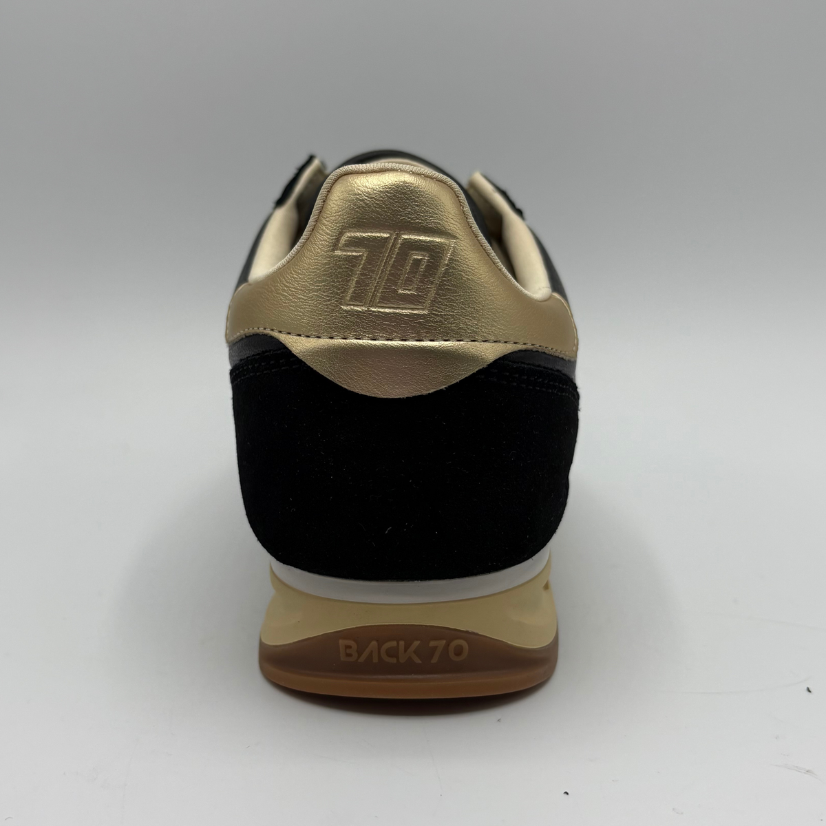 Back  view of a black leather and suede sneaker with a gold “70” on the side