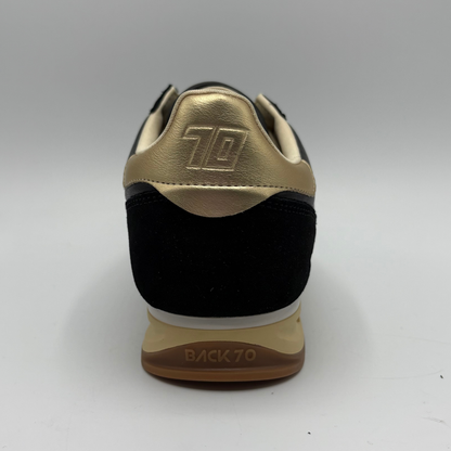 Back  view of a black leather and suede sneaker with a gold “70” on the side