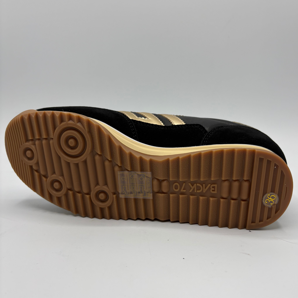 Bottom  view of a black leather and suede sneaker with a gold “70” on the side