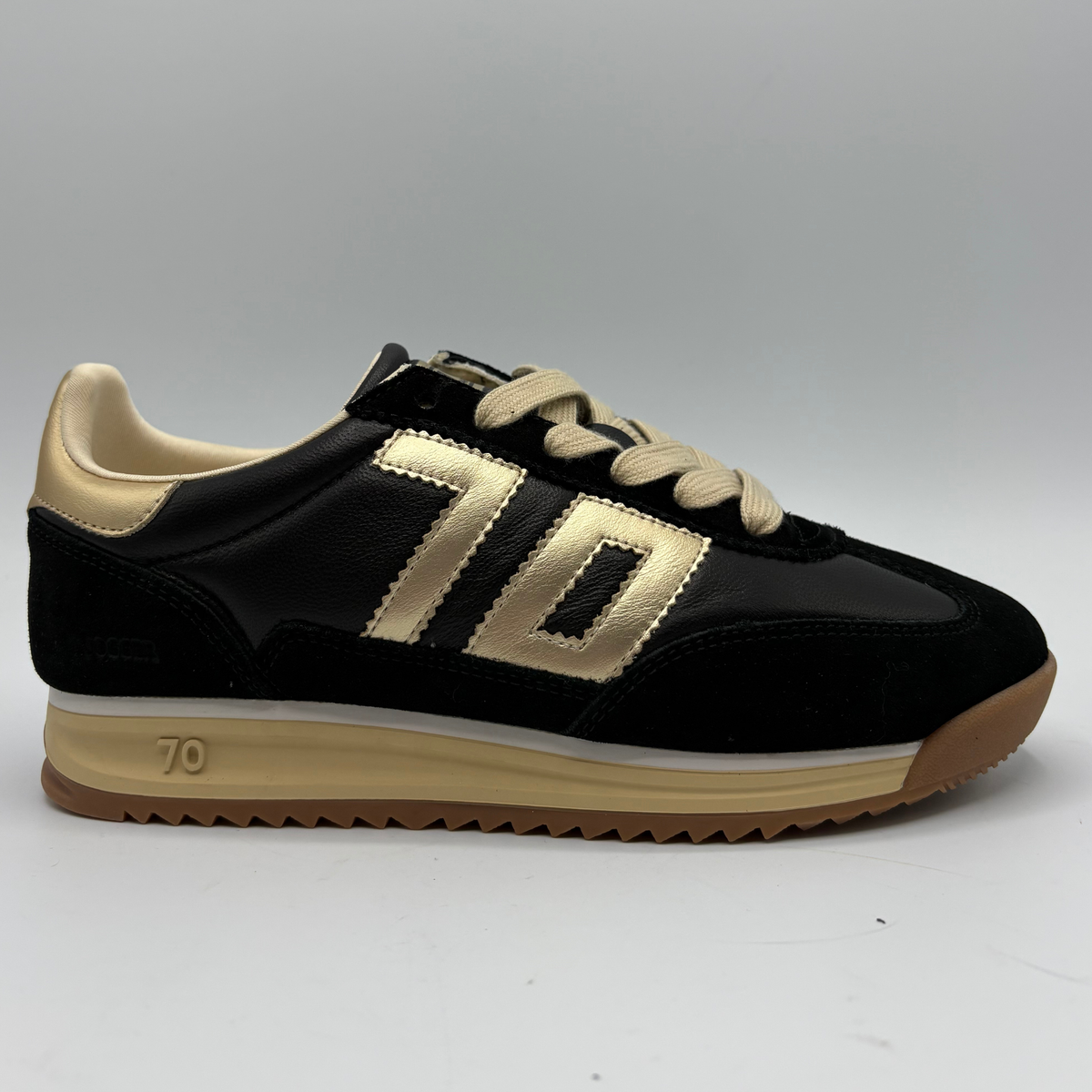 Right facing view of a black leather and suede sneaker with a gold “70” on the side