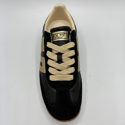 A single black and beige low-top sneaker shown from a top-down view on a light gray background. The shoe features black leather panels, beige suede overlays, beige laces, and a tan outsole.