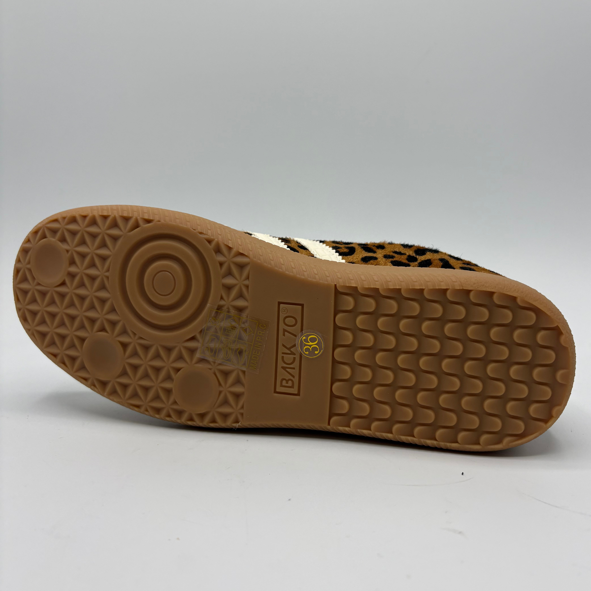A low-top sneaker featuring a brown and black leopard print pattern on the upper, cream-colored “70”, a cream collar lining, and a brown gum sole with 'BACK 70' embossed on the heel.