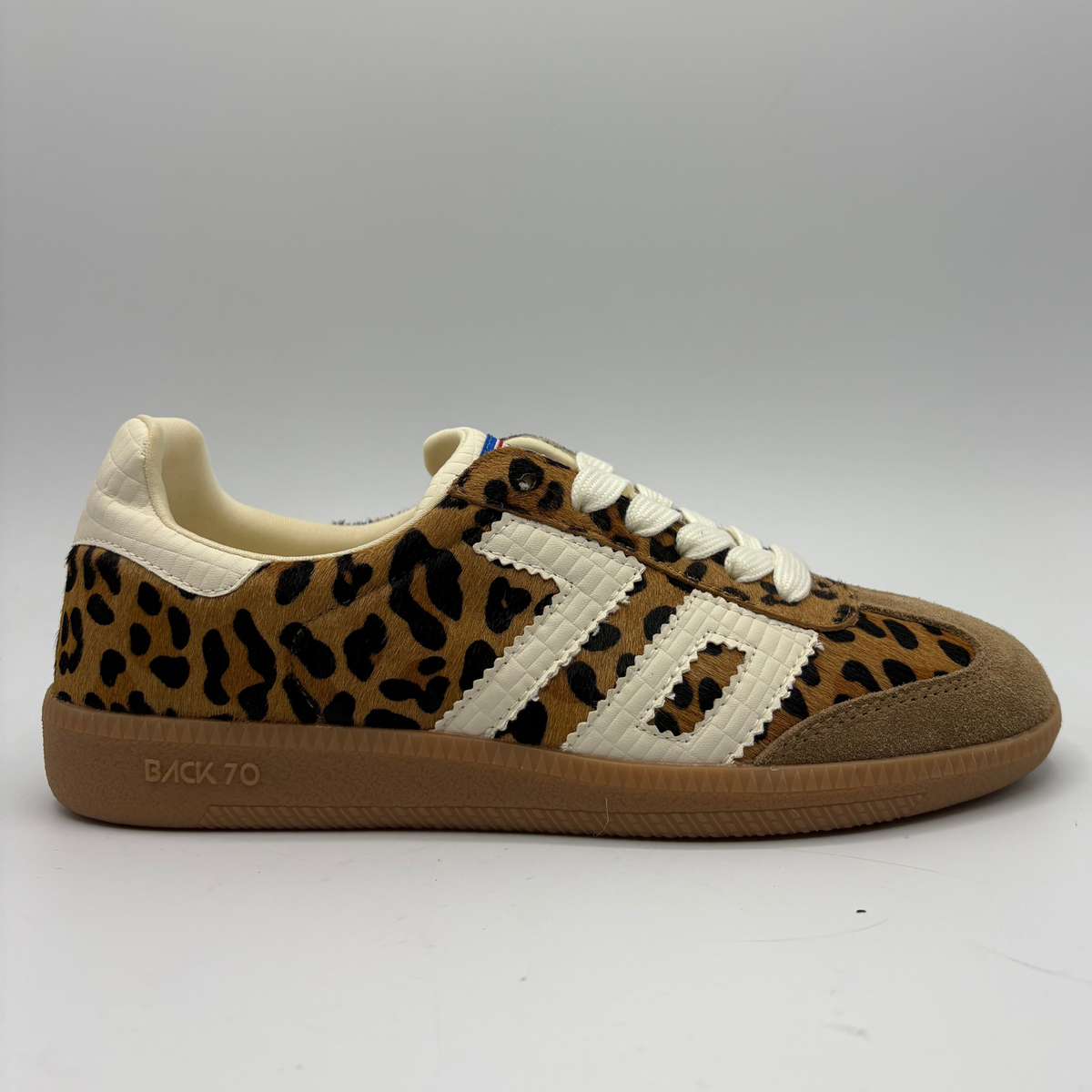 A low-top sneaker featuring a brown and black leopard print pattern on the upper, cream-colored “70”, a cream collar lining, and a brown gum sole with 'BACK 70' embossed on the heel.