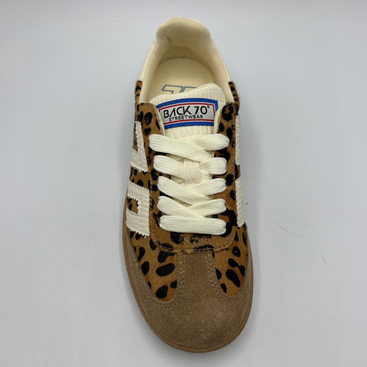 A low-top sneaker featuring a brown and black leopard print pattern on the upper, cream-colored “70”, a cream collar lining, and a brown gum sole with 'BACK 70' embossed on the heel.