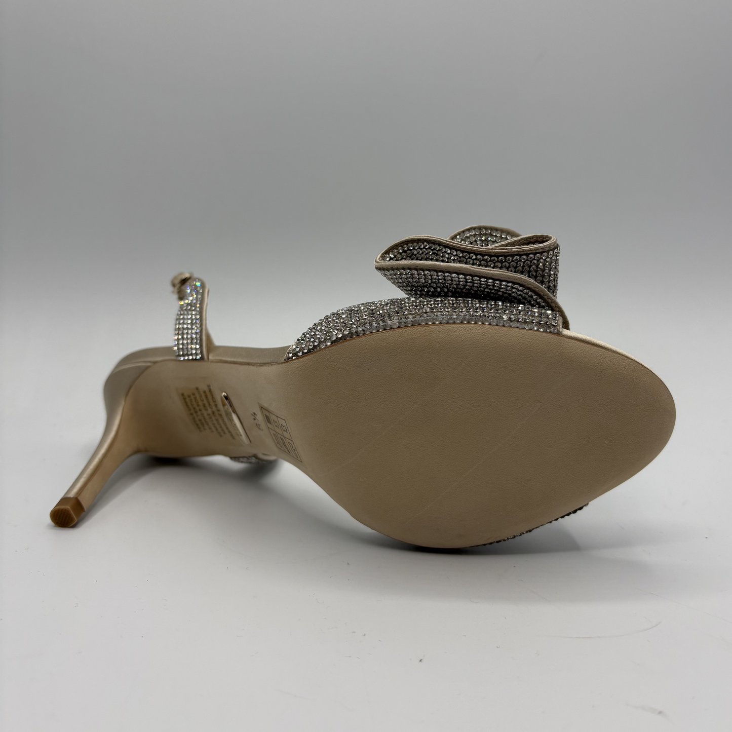 High-heeled shoe with decorative strap on a gray background