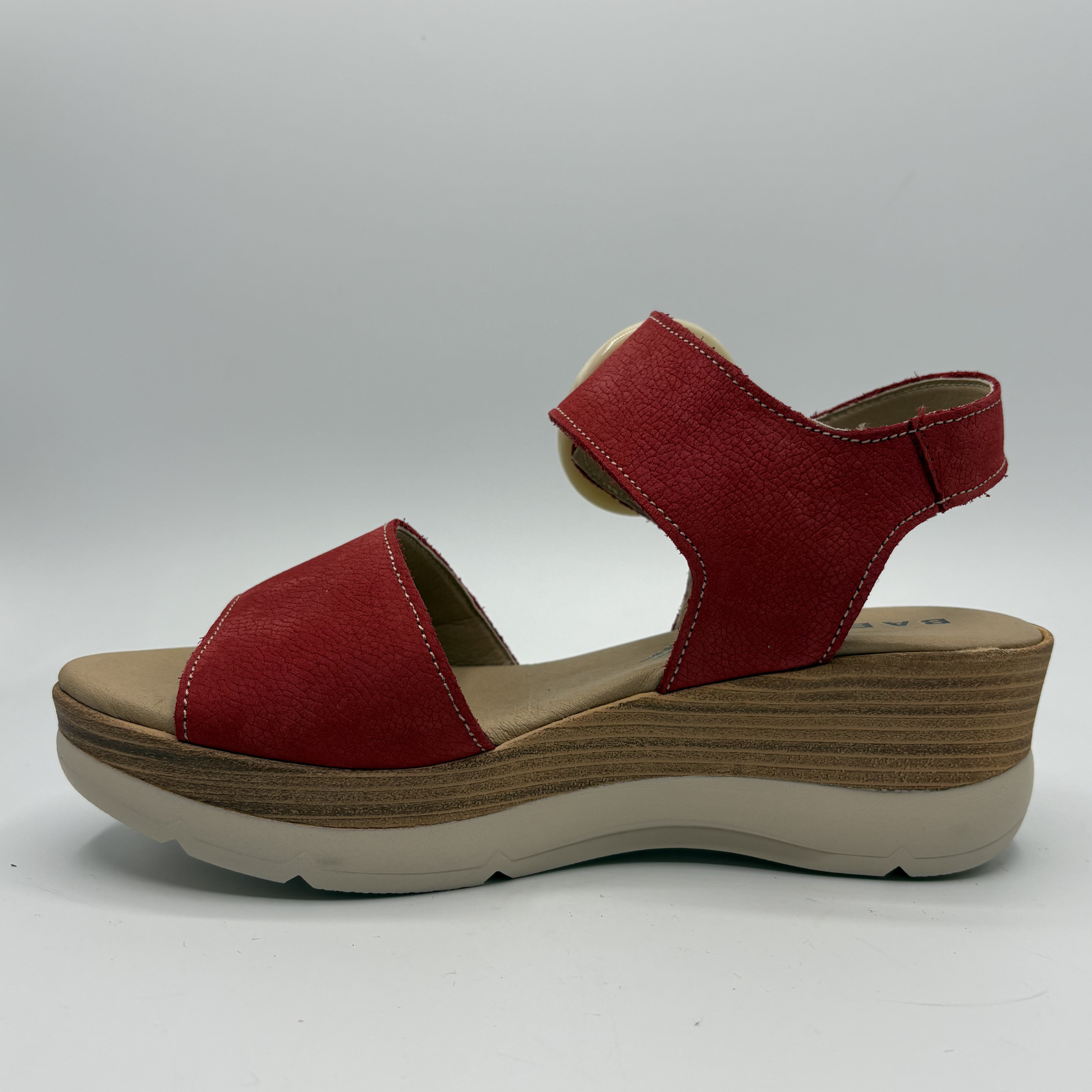 Red sandal with a wooden wedge sole on a white background