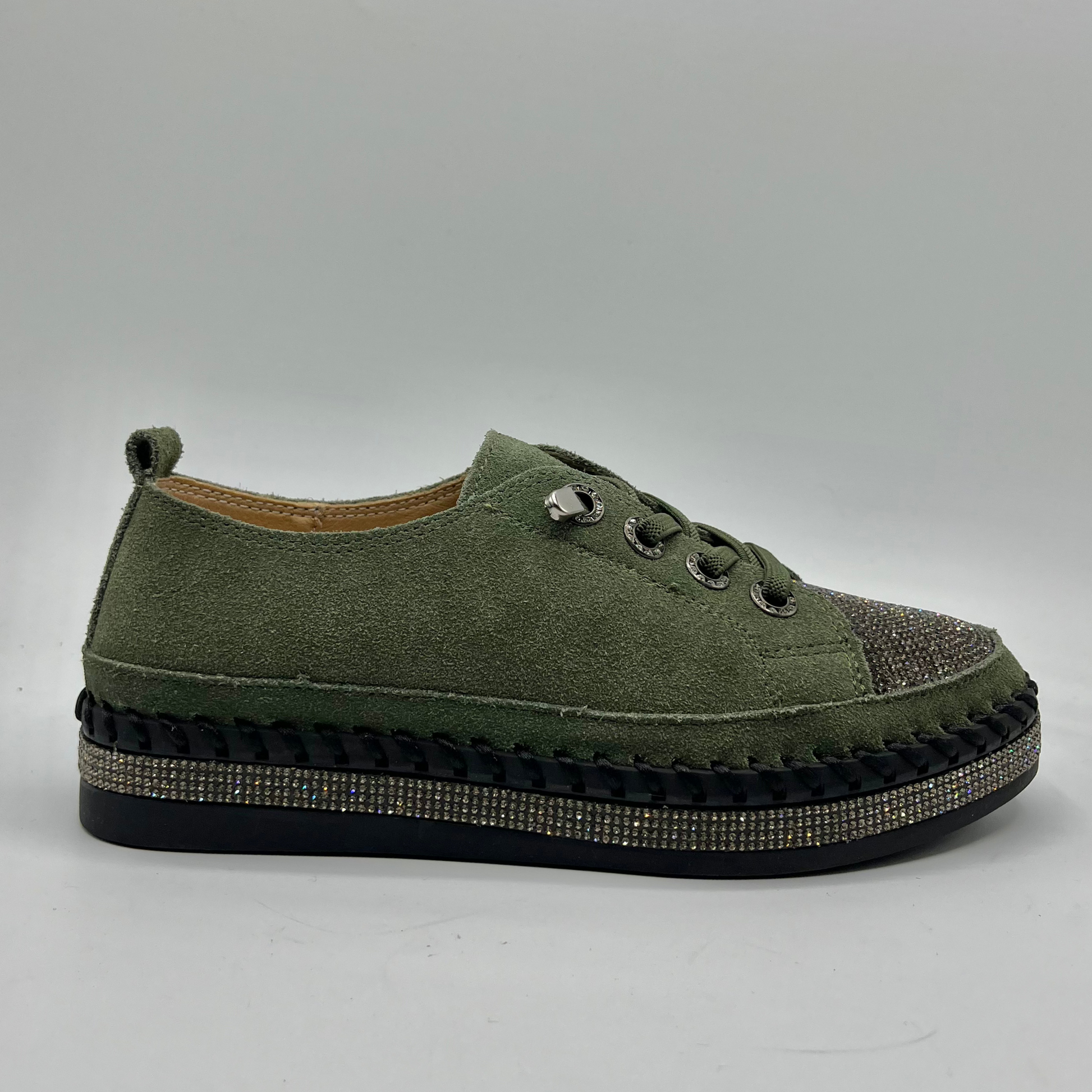 Green sneaker with embellished sole on a gray background