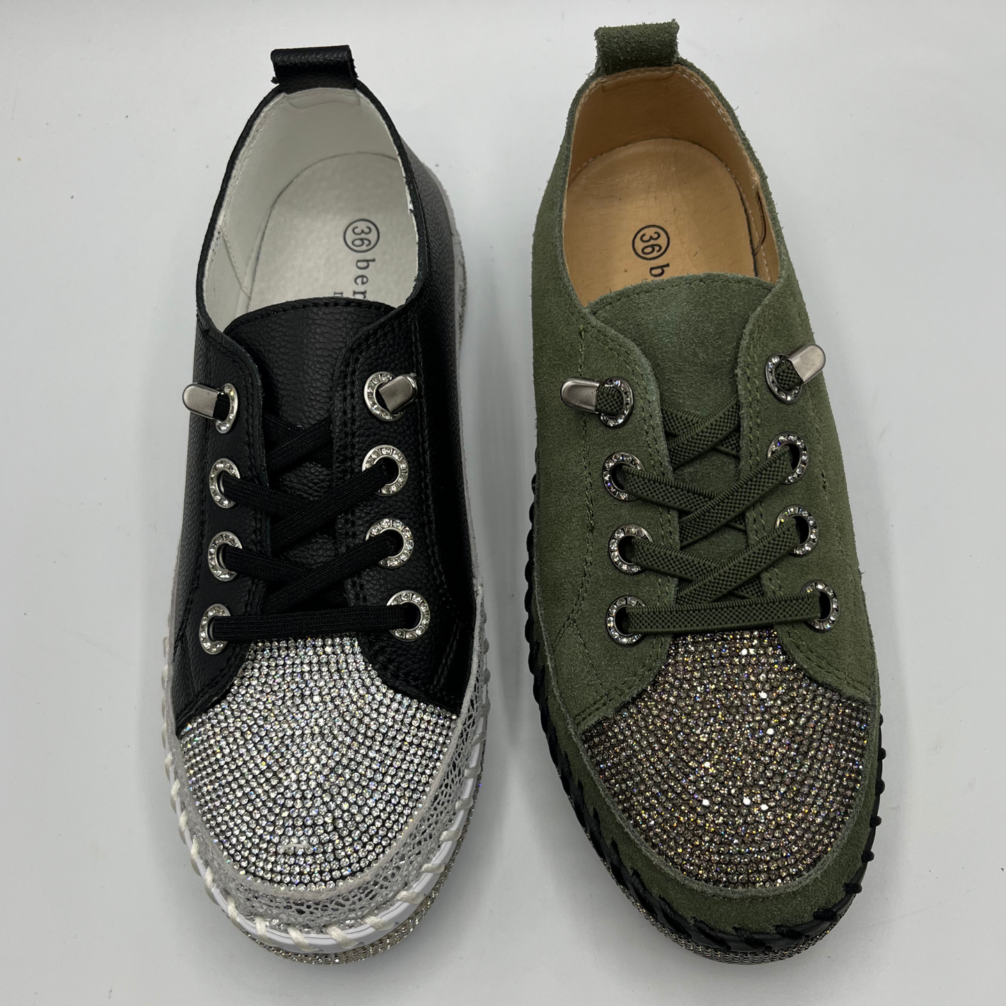 Pair of black and green sneakers with embellishments on a white background