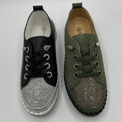 Pair of black and green sneakers with embellishments on a white background