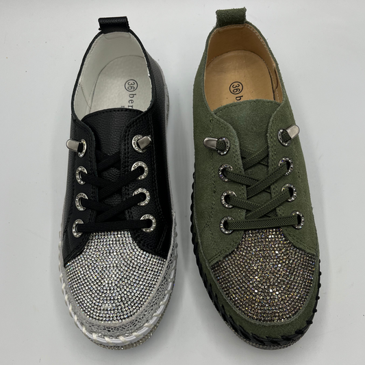 Pair of black and green sneakers with embellishments on a white background