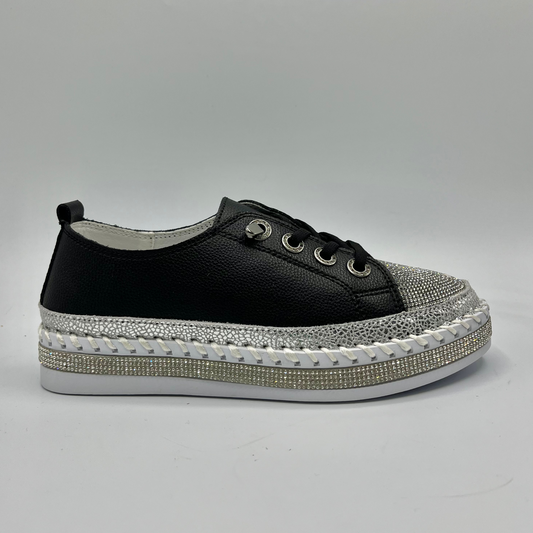 Black sneaker with silver embellishments on a gray background