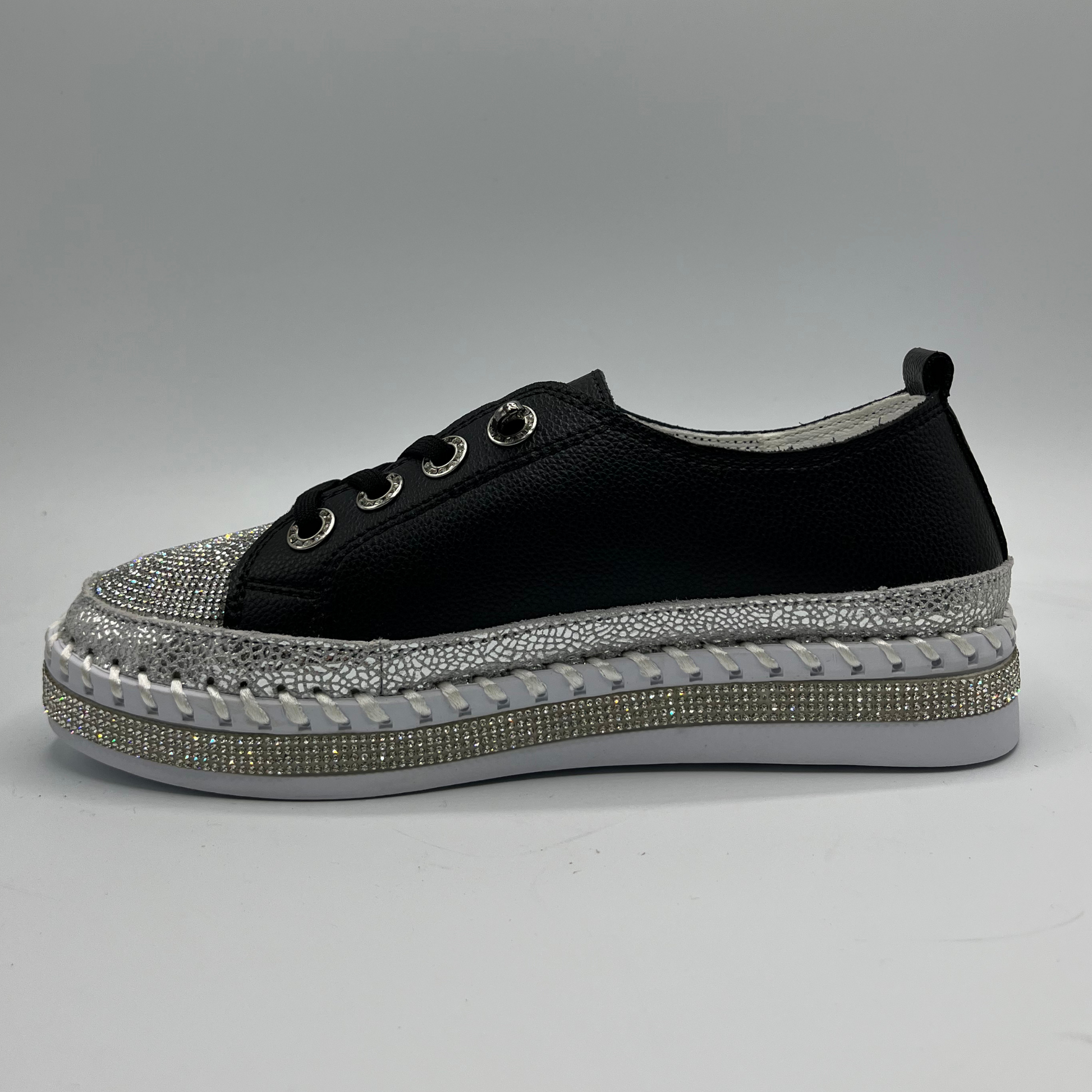 Black sneaker with a silver rhinestone sole on a gray background