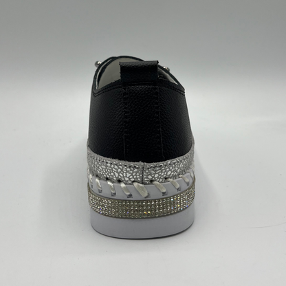 Black sneaker with silver embellishments on a gray background