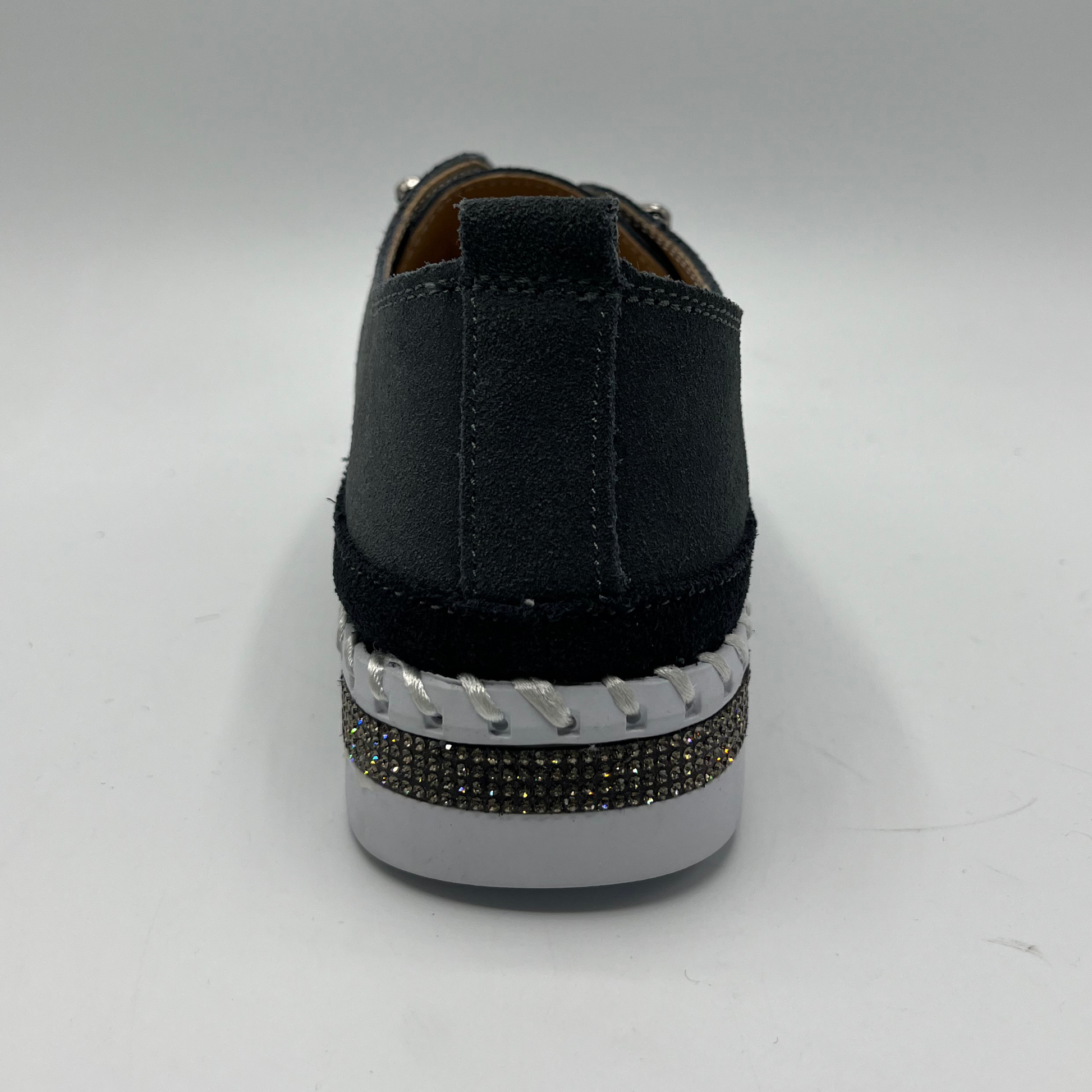 Dark grey sneaker with a white sole and decorative band on a gray background