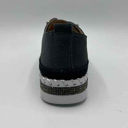 Dark grey sneaker with a white sole and decorative band on a gray background