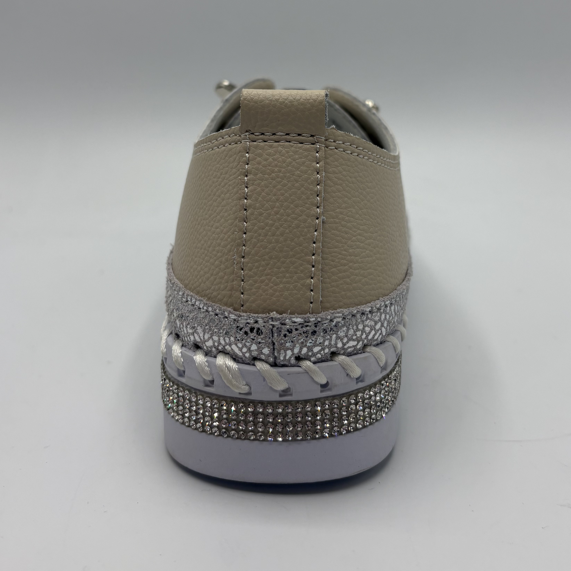 Brown sneaker with decorative silver rhinestone trim on a gray background