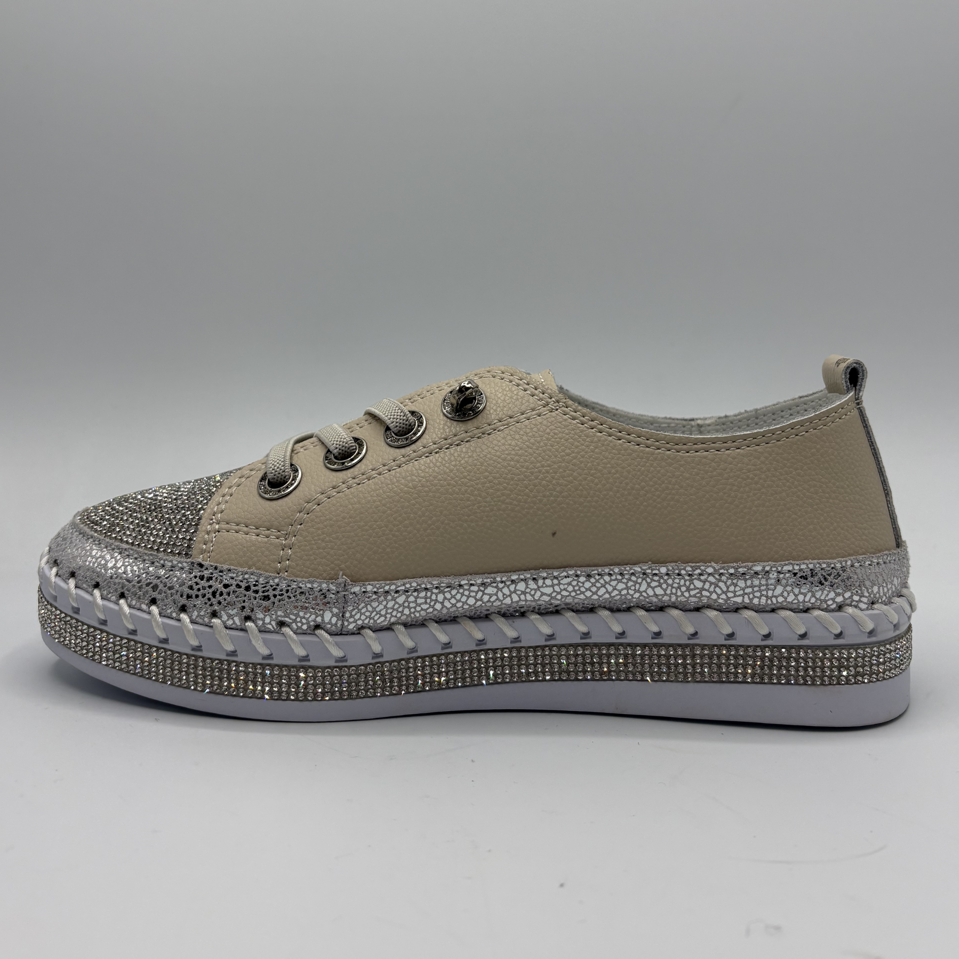 Beige sneaker with silver embellishments on a gray background