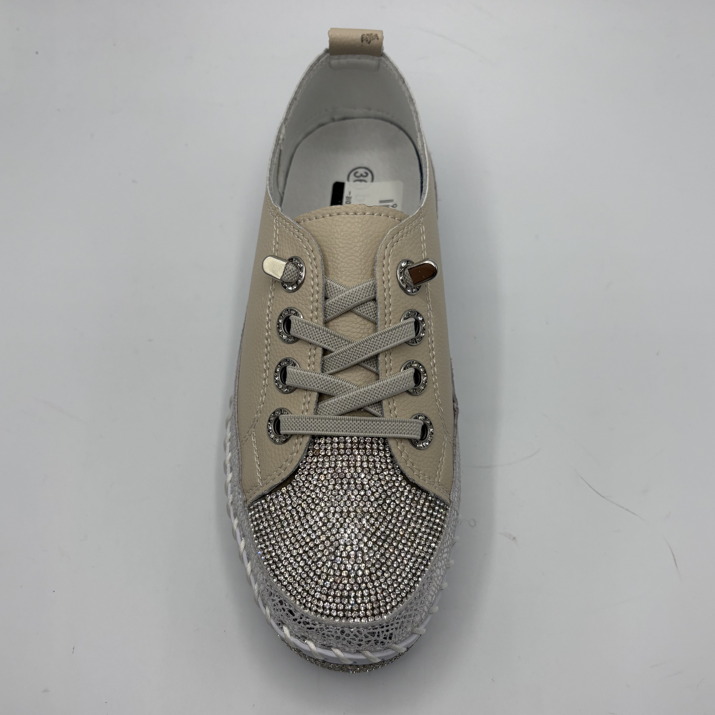 Beige sneaker with rhinestone embellishments on a gray background