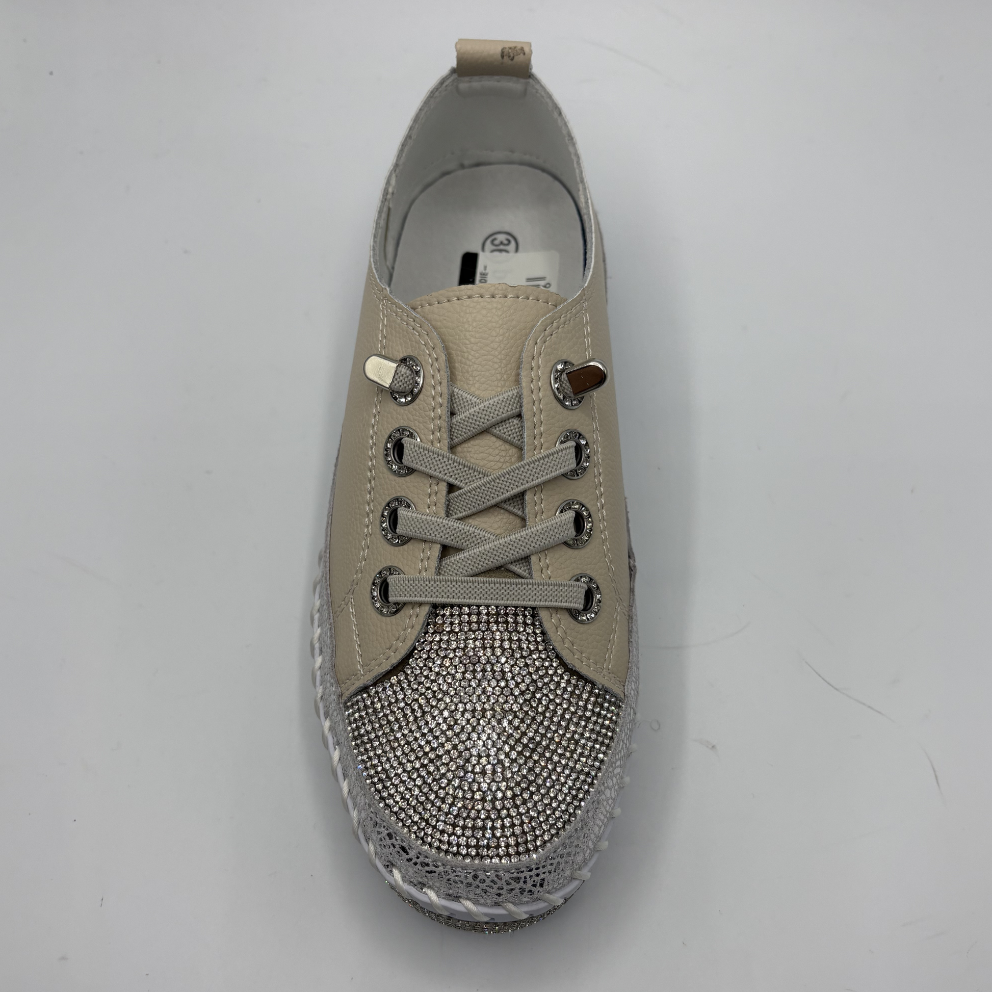Beige sneaker with rhinestone embellishments on a gray background