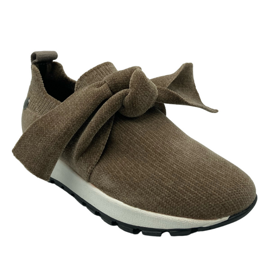 45 degree angled view of brown slip on sneaker with large bow detail on upper and thick rubber outsole