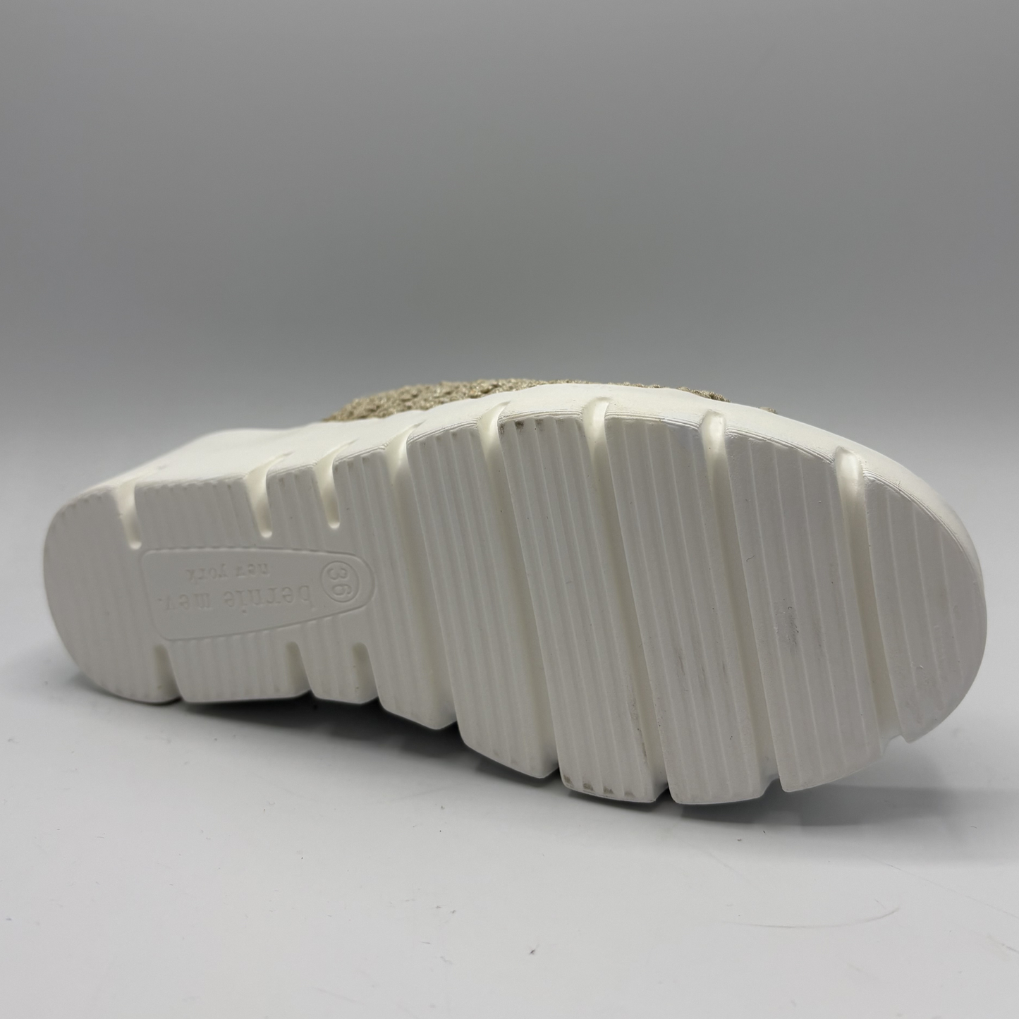 Close-up of a white sole with tread pattern on a gray background