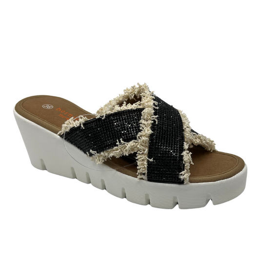 45 degree angled view of black rhinestone strapped sandals with fringe detail and white wedge heel