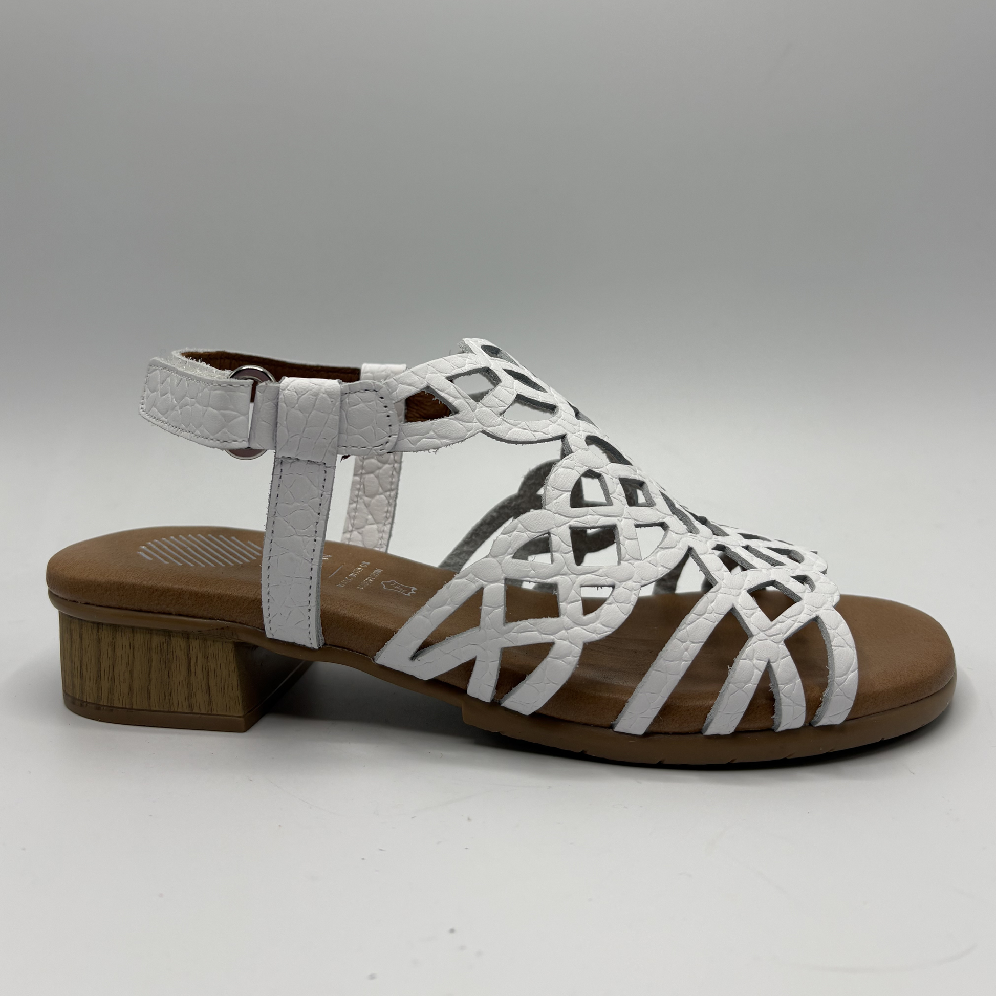 White sandal with brown sole on a gray background