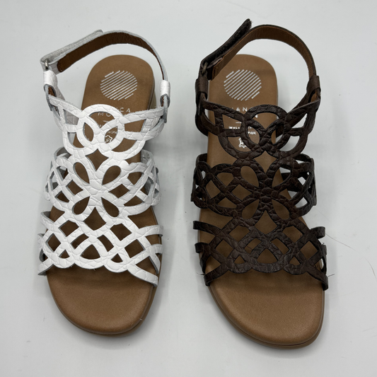 Pair of white and brown sandals with intricate designs on a light gray background