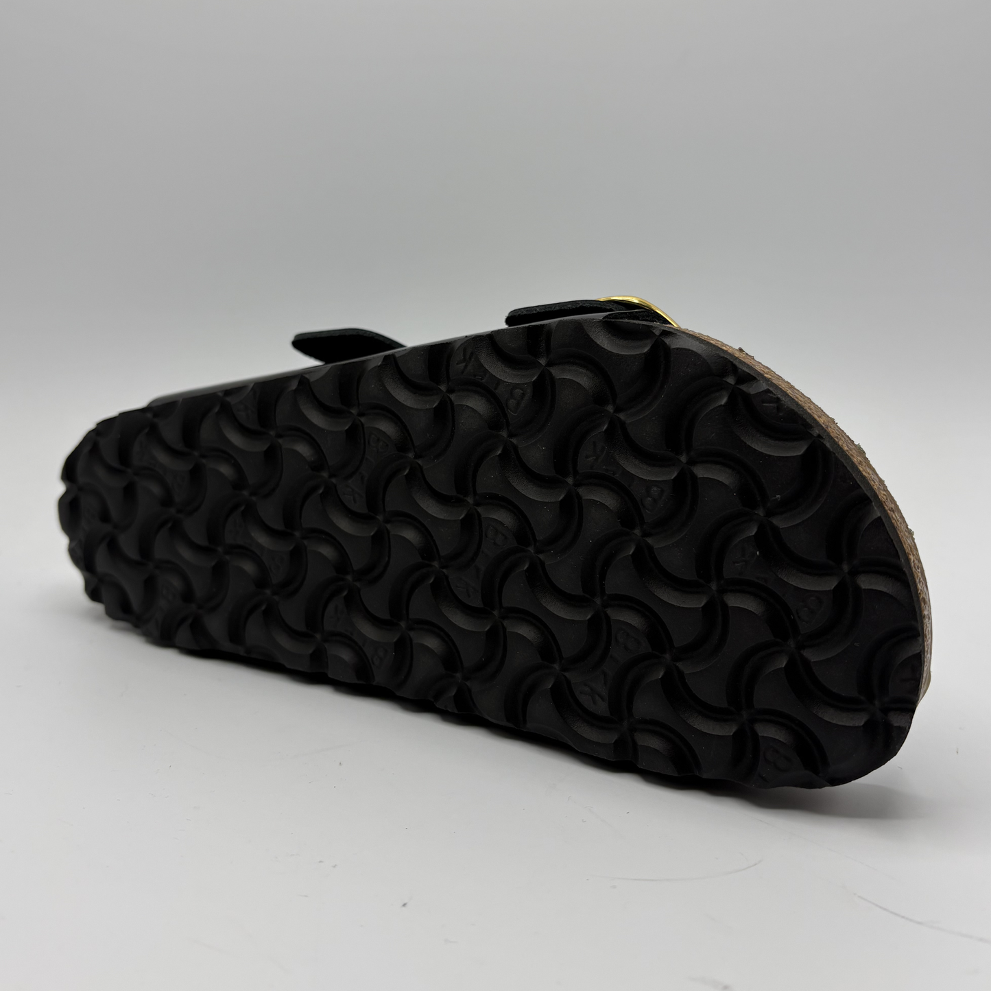 Black sandal with textured sole on a gray background
